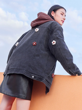 the back view of a lady in black denim flower jacket